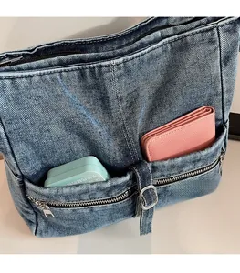 Detail of blue denim tote bag featuring dual front zipper pockets for easy storage