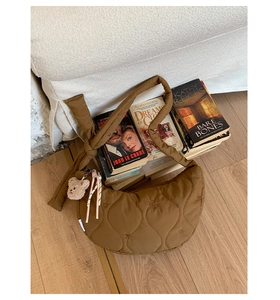 Détail du matelassage en forme de cœur sur un sac marron avec un petit ours en peluche