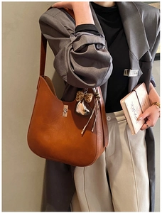 Close-up of caramel hobo bag featuring metal twist lock and heart leopard plush charm