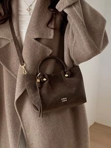 Minimalist dark coffee suede bucket bag with gold hardware and shoulder strap
