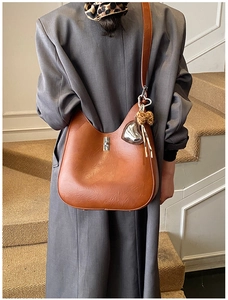 Rear view of model wearing a caramel brown leather hobo bag with a silver heart charm