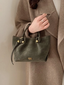 Minimalist olive green bucket bag with gold hardware and smooth leather texture