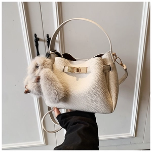 Detail of white lychee leather bucket bag with gold twist lock and plush bunny charm
