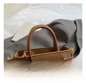 Detail of brown woven bucket bag with pom-pom charm and golden hardware on fabric
