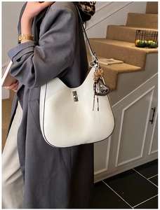Detail of white half-moon bag featuring a silver twist lock and leopard print heart charm