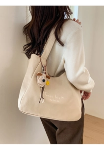Detail of minimalist cream canvas tote bag with shoulder strap and puppy plush charm