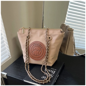 Detail of beige nylon bag with puppy leather patch and gold chain strap on books
