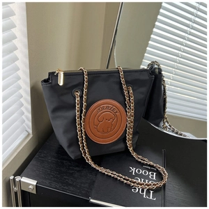 Detail of black nylon shoulder bag featuring a brown leather Pawlor logo and chain strap