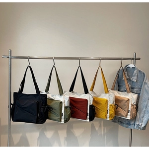 Multiple colors of casual tote bags with zipper pockets hanging on a silver rack