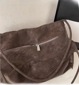 Detail of smooth metal zipper closure on deep brown textured leather tote bag