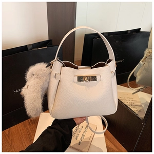 Close-up of cream white bucket bag with golden hardware and cute bunny pendant charm