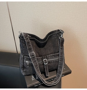 Close-up of vintage grey denim crossbody bag with utility buckles and zippers on books