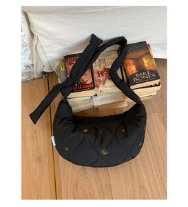 Gros plan du sac hobo matelassé noir avec broderies d'étoiles dorées et détails