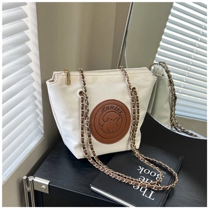 Detail of white nylon tote with Panier leather patch and dog relief with gold chain strap