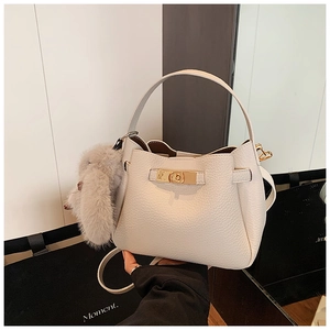 Detail view of white lychee leather bucket bag with gold hardware and plush rabbit charm