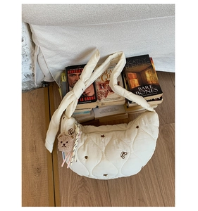 Détail du sac croissant matelassé beige avec broderie ours et pendentif en peluche
