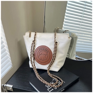 Close-up of white nylon bag with brown leather dog patch and gold chain strap