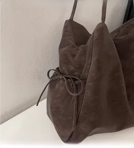 Detail view of vintage dark brown leather tote bag featuring side bow drawstring and logo