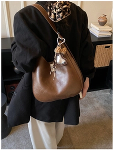 Detail of brown pleated hobo bag with silver heart charm and leopard print accessory