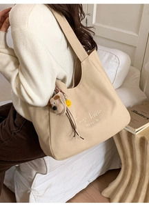 Close-up of beige canvas tote bag with C'est la vie text and puppy plush keychain