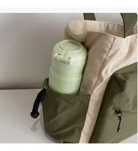 Detail of side pocket with drawstring holding a water bottle on a canvas tote bag