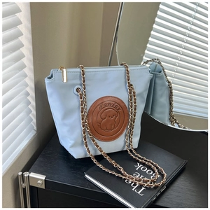 Close-up of light blue chain bag featuring a brown leather dog emblem on the front