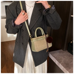 Detail of beige woven bucket bag with sage green trim, plush charm and silk scarf