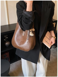 Detail view of a vintage brown leather bucket bag with silver buckle and leopard heart charm