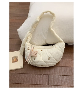 Détail du sac croissant matelassé crème avec broderie ours et pendentif en peluche