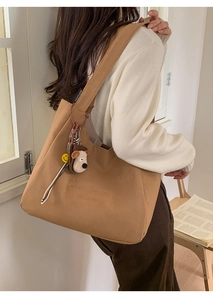 Detailed view of camel canvas tote bag with C'est la vie embroidery and plush puppy charm