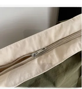 Detail of smooth metal zipper and durable canvas stitching on olive green shoulder bag