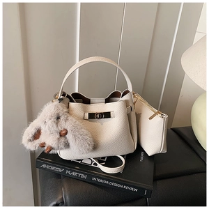 Detail of off-white leather bucket bag with gold clasp and plush rabbit pendant charm