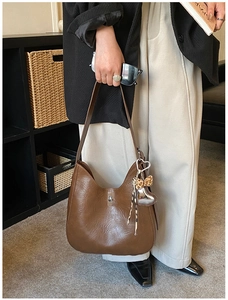 Detail of vintage brown leather handbag featuring silver twist lock and leopard bow charm