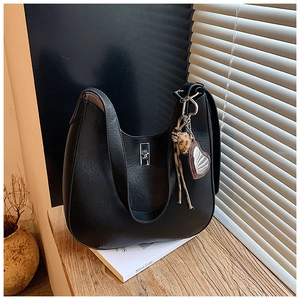 Detail of black pebbled leather crescent bag with silver twist lock and heart charm