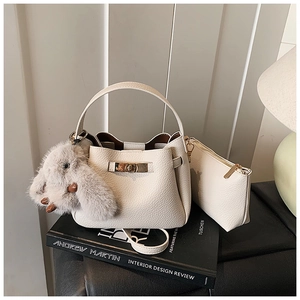 Detail of creamy white pebble leather bucket bag with plush rabbit charm and inner pouch