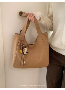 Detail of khaki canvas tote bag with C'est la vie embroidery and cute puppy charm