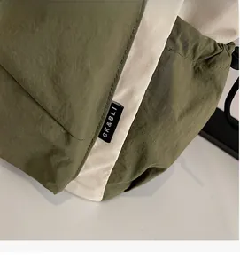 Detail of army green nylon tote bag featuring durable stitching and drawstring closure
