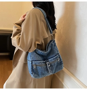 Detail of blue denim tote bag with silver zippers and wide shoulder strap