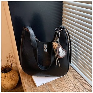 Close-up of black hobo bag featuring silver twist lock and heart pendant accessory