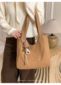 Detail of khaki canvas tote bag with embroidery, cute plush puppy charm and brand label