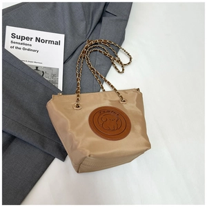 Detail of khaki nylon tote with cartoon puppy leather patch and metal chain strap