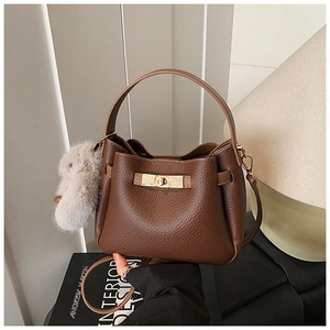 Detail of dark brown lychee leather texture and golden metal twist lock on bucket bag