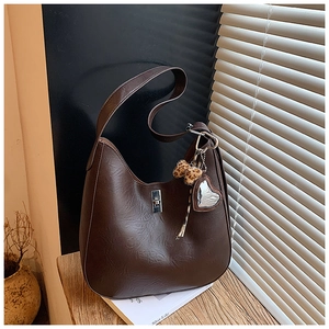 Detail of dark brown faux leather hobo bag with leopard pompom and heart charm