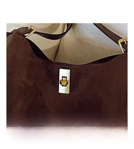 Detail of vintage golden metal buckle on brown suede large capacity shoulder bag