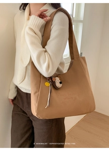 Detail of brown canvas tote bag with embroidery and cute puppy and smiley face charms