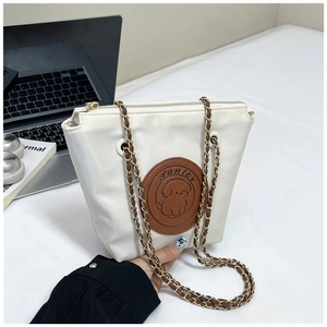 Detail of white nylon shoulder bag featuring a cartoon puppy patch and gold chain strap