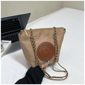 Detail of khaki nylon tote bag with embossed cartoon dog leather patch and gold chain strap