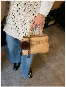 Détail du sac seau tissé marron clair avec sangle décorative et pompon marron doux