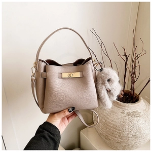 Detail of taupe pebbled leather bucket bag with gold clasp and grey bunny charm
