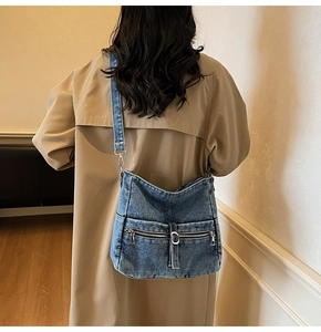 Close-up of retro washed denim crossbody bag with dual zipper pockets on a model